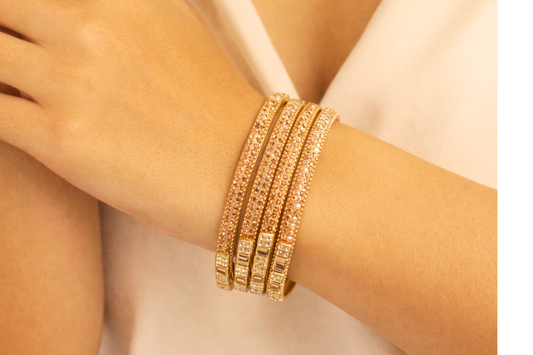 Gold bracelet on a wrist with a neutral background