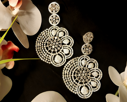 Ornate gold earrings on a dark background with flowers.